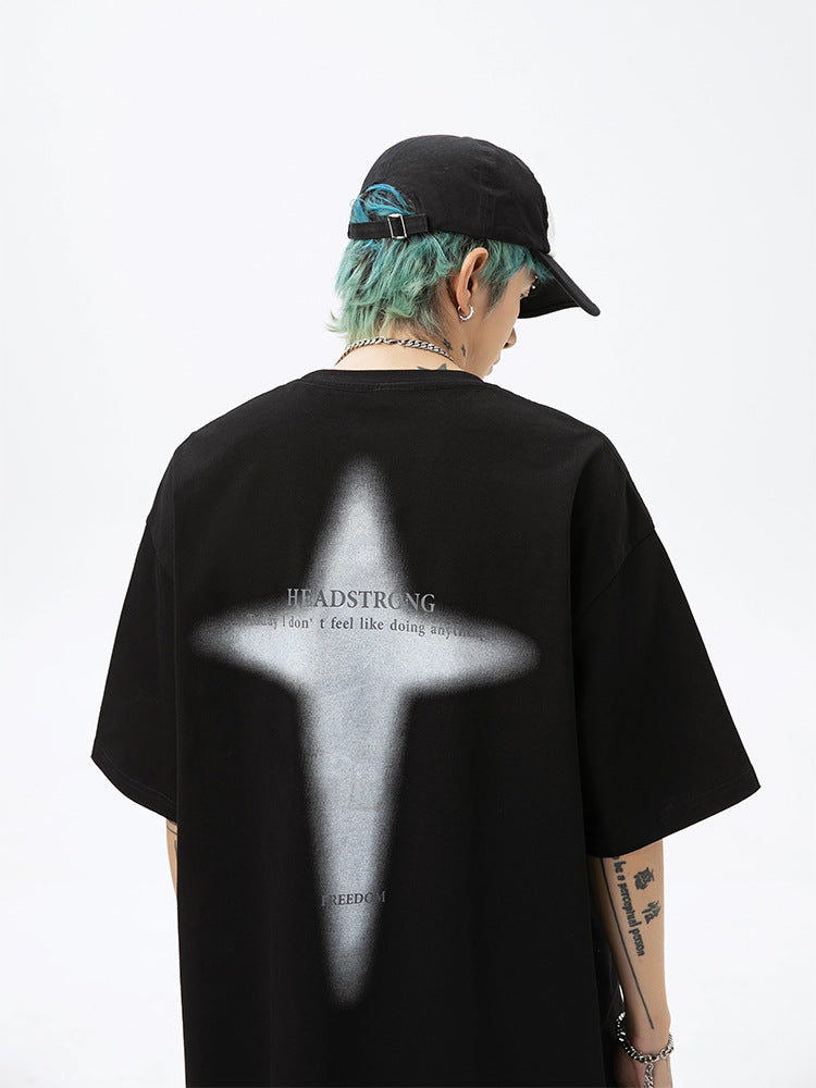 A man is shown from behind wearing black tee with contrasting white cross graphic. Features blue-green hair, black cap and small neck tattoo visible