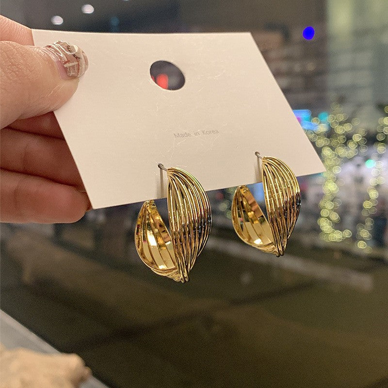 Gold Wire Hoop Earrings – Modern gold hoop earrings with layered wire details, displayed on a card with a blurred cityscape background