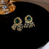 Elaborate gold chandelier earrings with emerald green stones, featuring a cascading fan-like design with multiple tiers