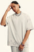 Portrait of model with hand to forehead wearing light beige t-shirt and silver chain. Features minimalist styling with subtle washed fabric effect