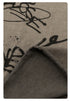 Fabric texture detail showing black graffiti designs on soft taupe cotton jersey material