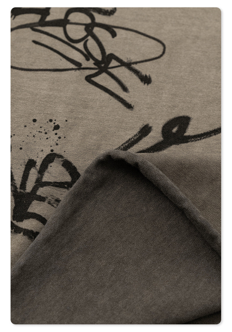 Fabric texture detail showing black graffiti designs on soft taupe cotton jersey material