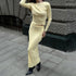 Woman wearing cream ribbed two-piece set with long skirt and pointed black boots on urban sidewalk, street style fashion
