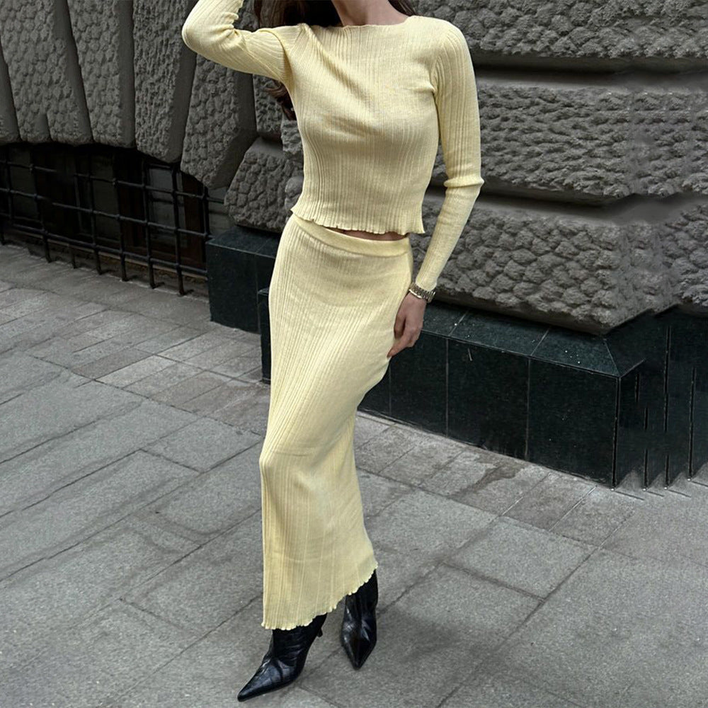 Woman wearing cream ribbed two-piece set with long skirt and pointed black boots on urban sidewalk, street style fashion