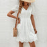 Woman wearing a white eyelet lace dress with a straw hat and a woven shoulder bag, creating a summery, boho-chic look