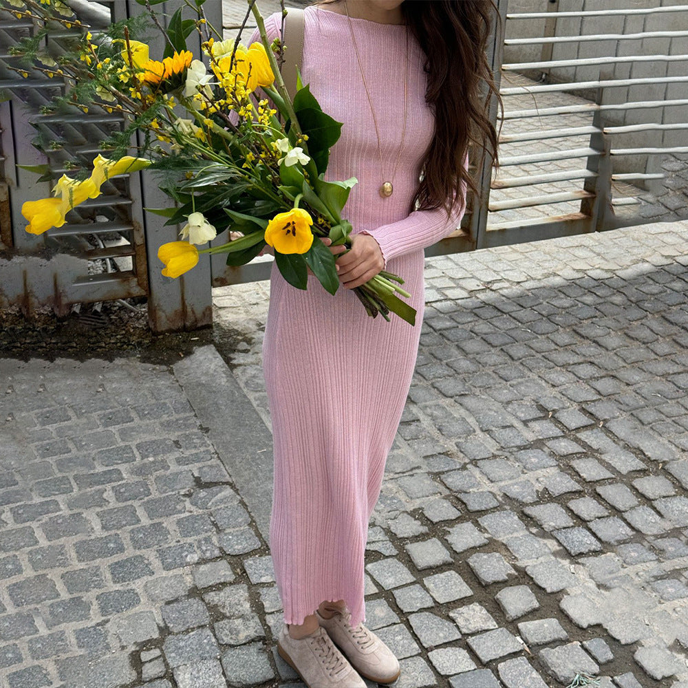 Model in pink ribbed maxi dress holding spring bouquet with yellow tulips and sunflowers against cobblestone backdrop