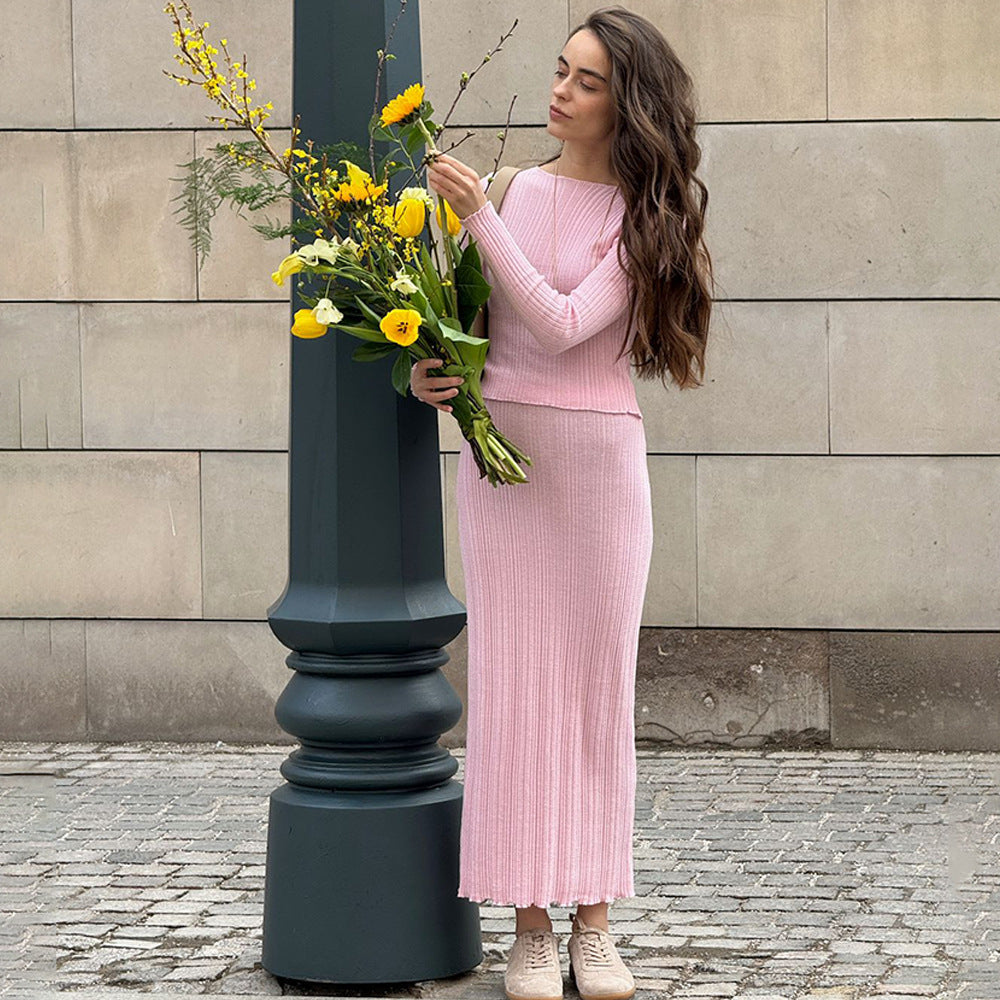 Long pink ribbed dress styled with sneakers and yellow spring flowers, casual street style against architectural column