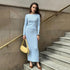 Light blue fitted ribbed dress with cream baguette bag against concrete staircase, minimalist urban fashion look