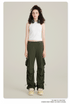 Model in white racerback tank top and olive cargo pants with utility pockets and adjustable drawstring hem. Black headphones rest on shoulders