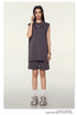 Model talking on phone wearing dark gray sleeveless top and shorts set, silver chain necklace and sunglasses on neutral background