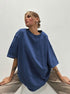 Person wearing a blue oversized t-shirt against a plain background