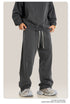 Person in black hoodie with charcoal sweatpants featuring white drawstring, showing fabric texture and relaxed fit