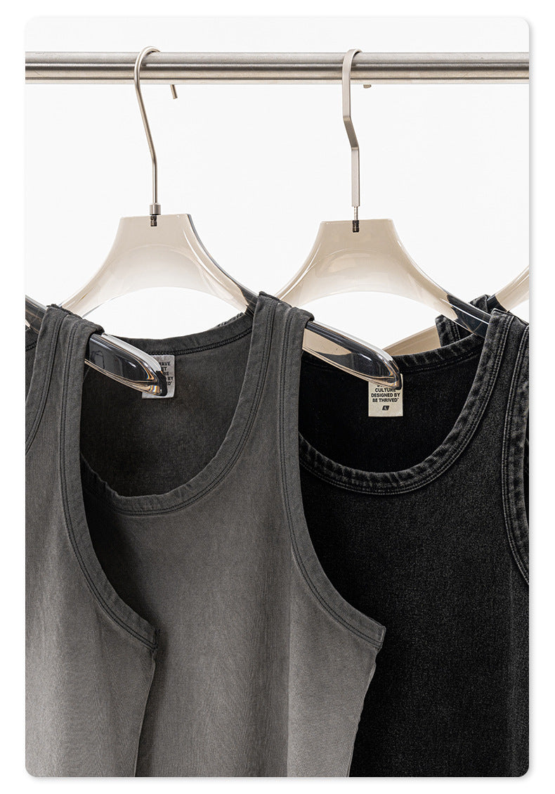 Close-up of gray and black sleeveless tank tops on clear hangers, showing washed fabric texture and branding tag