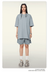 Woman seen from behind wearing light blue oversized T-shirt and matching shorts with white socks and sneakers