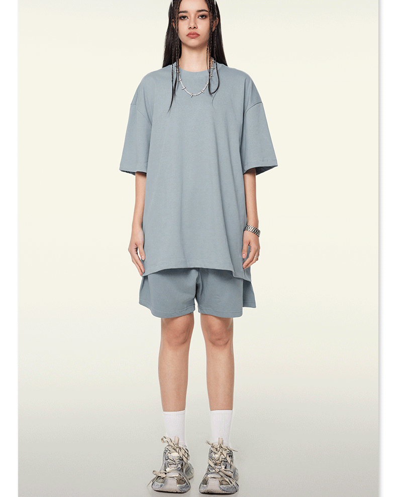 Woman seen from behind wearing light blue oversized T-shirt and matching shorts with white socks and sneakers