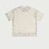 Light beige oversized t-shirt displayed flat showing subtle wash effect and brand tag. Features boxy silhouette and crew neckline