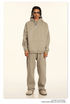 Model wearing beige hoodie and sweatpants with yellow-tinted sunglasses and coordinating footwear