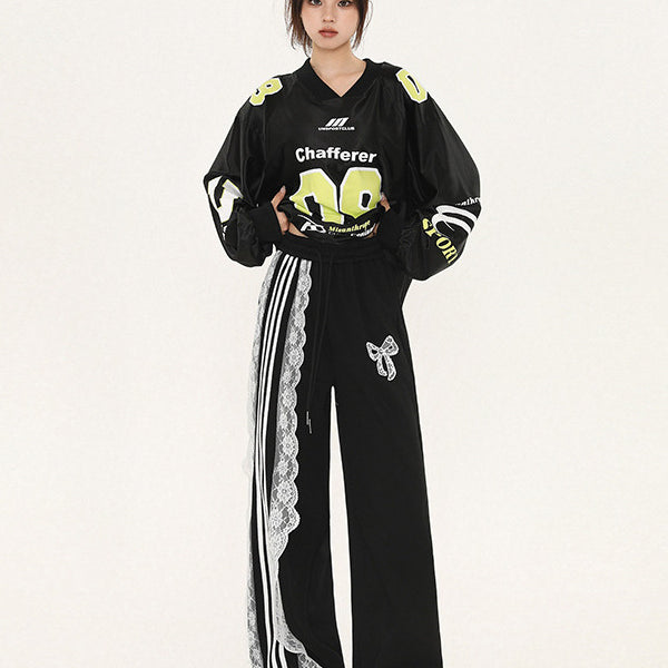 Model wearing black cropped jersey with 'Chafferer 08' in neon yellow, matching wide-leg pants with white lace and stripe detail, bow embellishment, athletic-inspired Y2K fashion