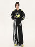 Model wearing black cropped jersey with 'Chafferer 08' in neon yellow, matching wide-leg pants with white lace and stripe detail, bow embellishment, athletic-inspired Y2K fashion