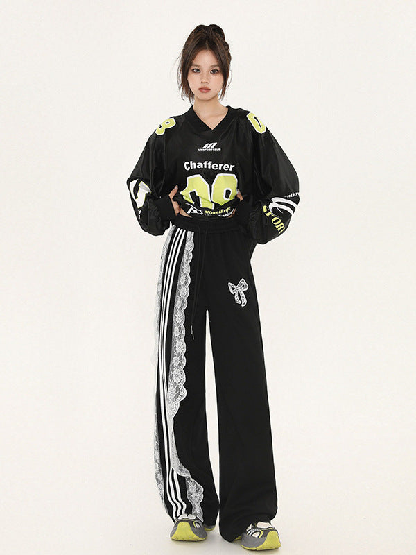 Model wearing black cropped jersey with 'Chafferer 08' in neon yellow, matching wide-leg pants with white lace and stripe detail, bow embellishment, athletic-inspired Y2K fashion