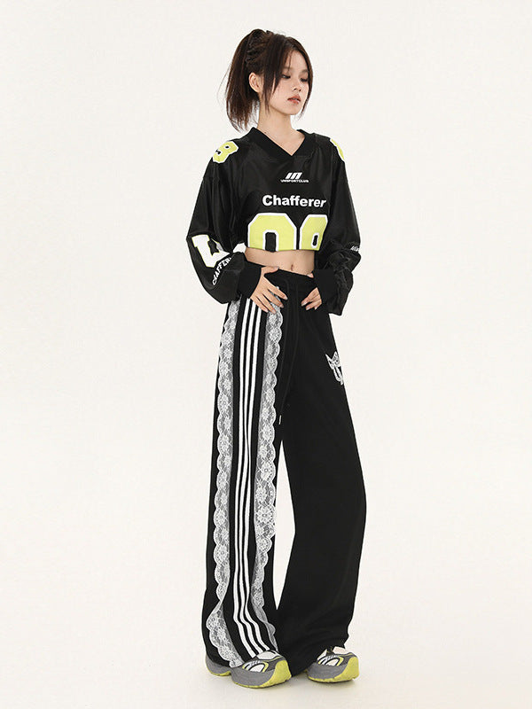 Model posing in black cropped sports jersey with neon yellow '08' numbering, high-waisted wide pants with white lace trim detail, hands at waist, minimalist background