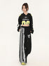 Front view of model in modified sports jersey crop top with 'Chafferer' logo, black wide-leg pants with decorative white lace panel, yellow-accented sneaker