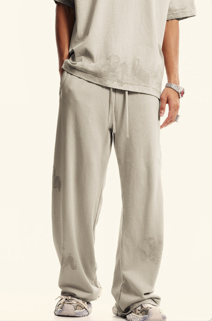Detail shot of beige t-shirt and matching pants with drawstring waist. Shows subtle distressed pattern effect and coordinated set styling.