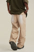 Back view of model with hands in pockets wearing olive shirt and beige utility pants