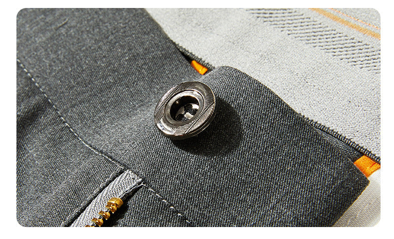 Close-up of metal button detail on gray dress pants fabric