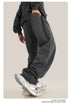 Person wearing black oversized sweatpants with detailed close-up of metallic sneakers and stacked pant hem