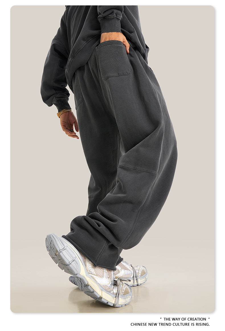 Person wearing black oversized sweatpants with detailed close-up of metallic sneakers and stacked pant hem
