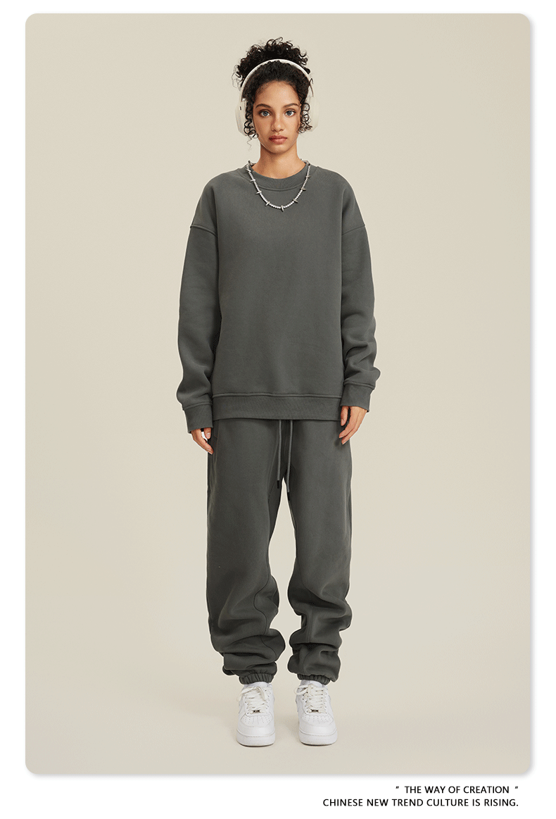 Model in dark gray sweatsuit with white headband, silver necklace and white sneakers