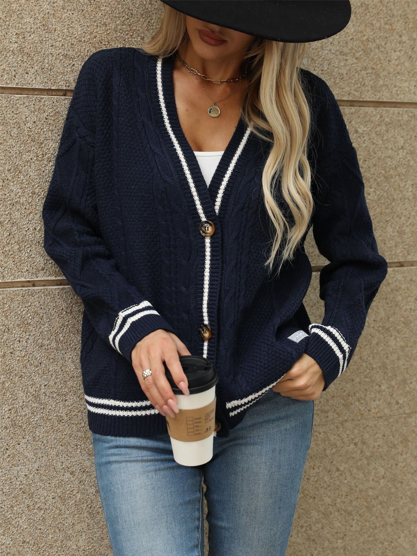 Navy cable knit cardigan with white contrast, styled with white top and coffee cup for preppy street style