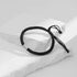 A black braided rope bracelet with a silver cylindrical charm featuring an intricate pattern, displayed on white stone slabs.