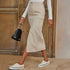 Close-up of cream midi cargo skirt with utility pockets and side slit, paired with off-white platform sneakers