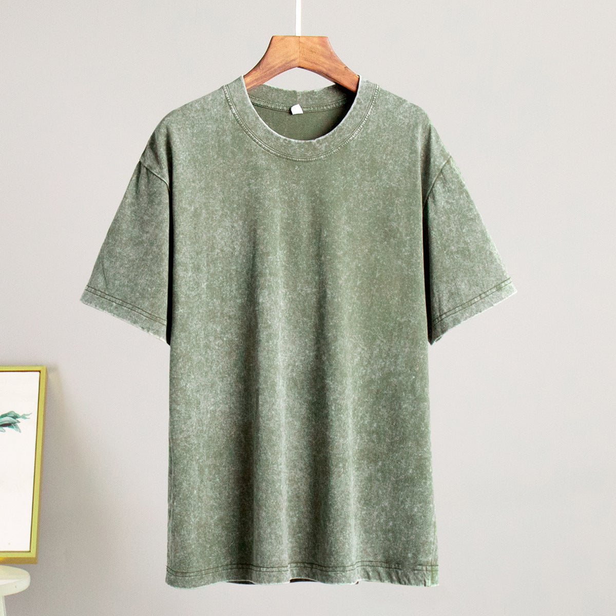 Green t-shirt on a hanger against a plain background