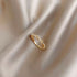Close-up of gold infinity-style ring with crystal details on silky fabric