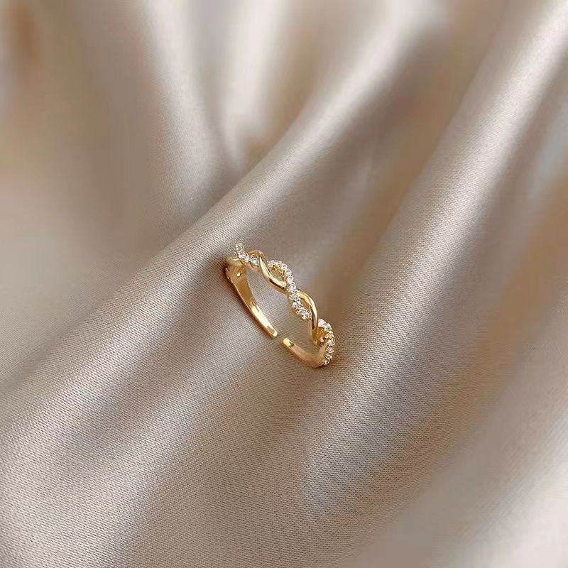 Close-up of gold infinity-style ring with crystal details on silky fabric
