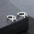 Cross charm huggie earrings on black display platform