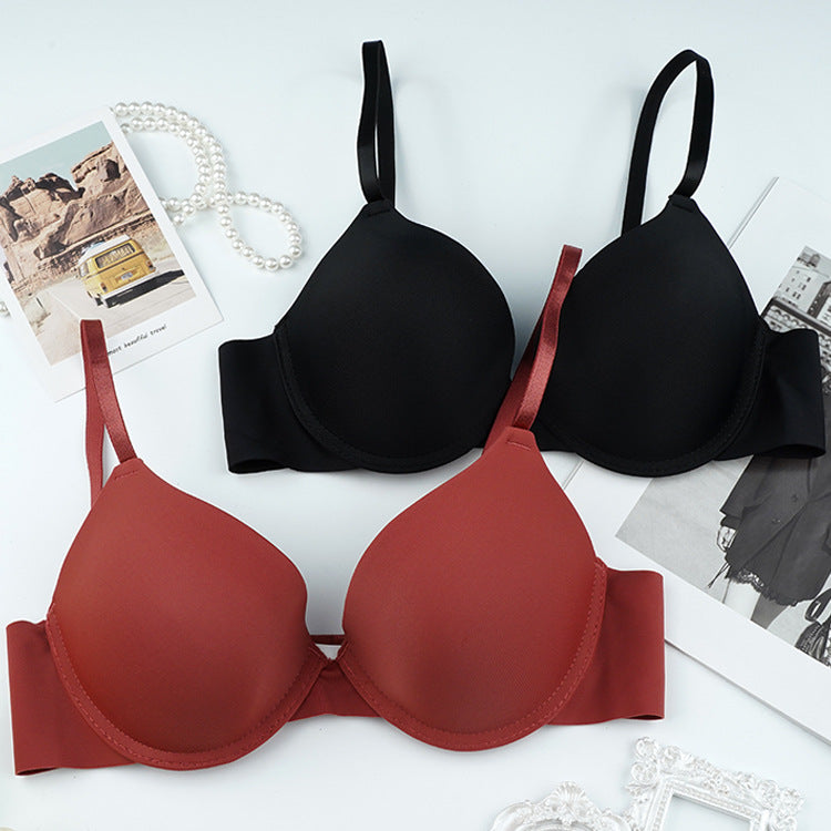 Product photo of rust and black padded bras laid flat on white surface with pearl necklace accessory