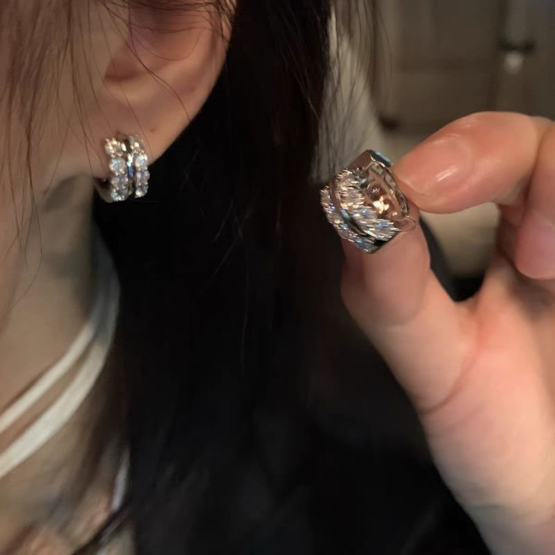 Crystal-lined silver huggie hoop earring shown on ear and held in hand, showing sparkle detail