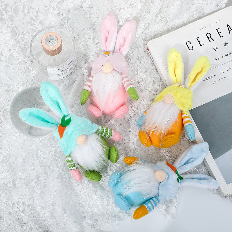 Four plush bunny gnome ornaments in pastel colors on lace fabric. Each has floppy ears, striped sleeves, and a soft beard.