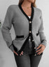 Gray knit cardigan with black trim, gold buttons, worn over white top and black jeans, woman standing against white wall