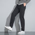 Side view of black pants with white drawstring and white sneakers, showing slim-fit design