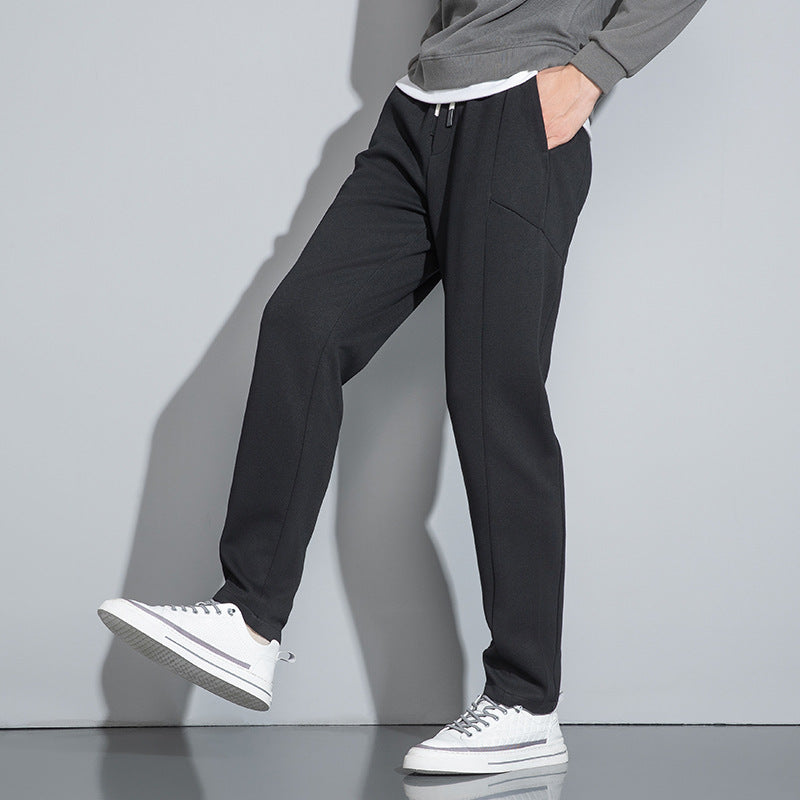 Side view of black pants with white drawstring and white sneakers, showing slim-fit design