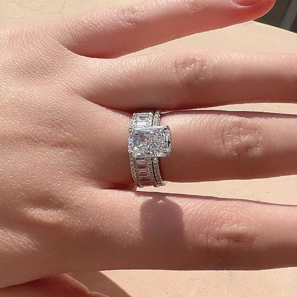 A woman displaying silver engagement ring with cushion-cut diamond center and baguette diamond accents on her hand in natural light