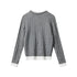 Grey cable knit cardigan with white trimmed crew neck, button-front closure, and layered white contrast hem. Ribbed cuffs with white detail. Back view,