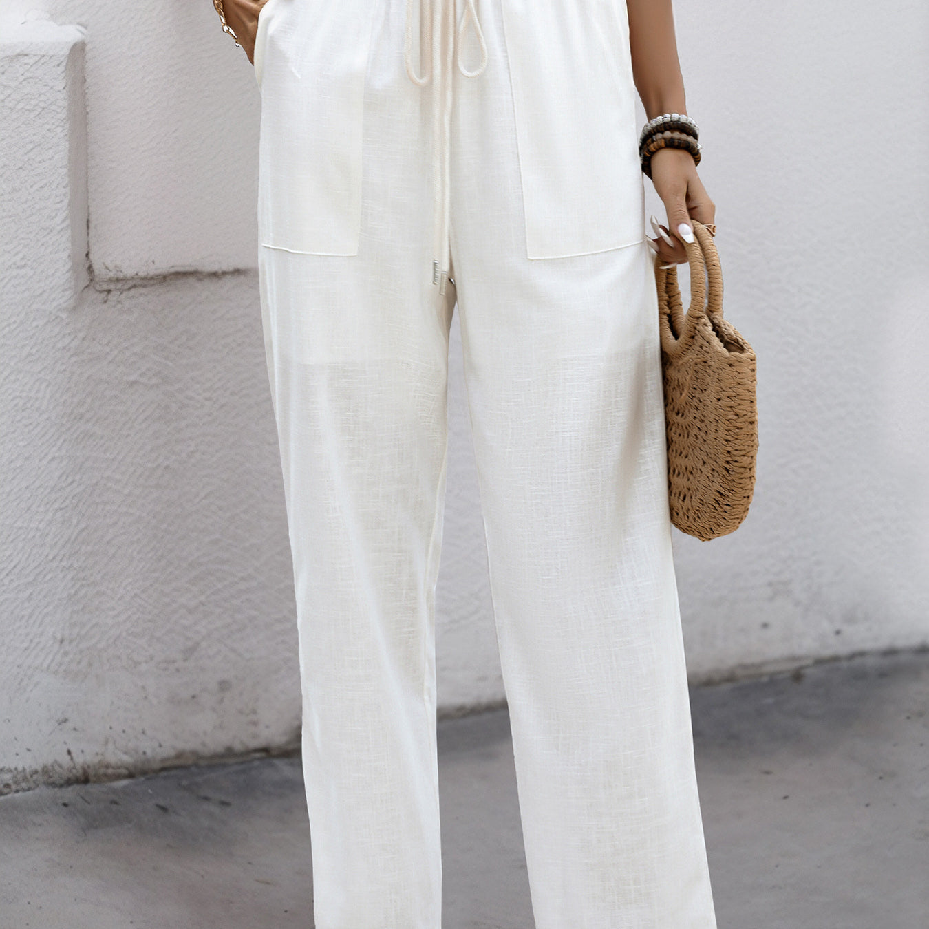 Woman wearing white wide-leg linen pants with an elastic drawstring waist, styled with a crop top and sandals.
