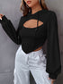 Side profile of woman in black cutout crop hoodie with bishop sleeves and white cargo pants, showing silver hoop earrings