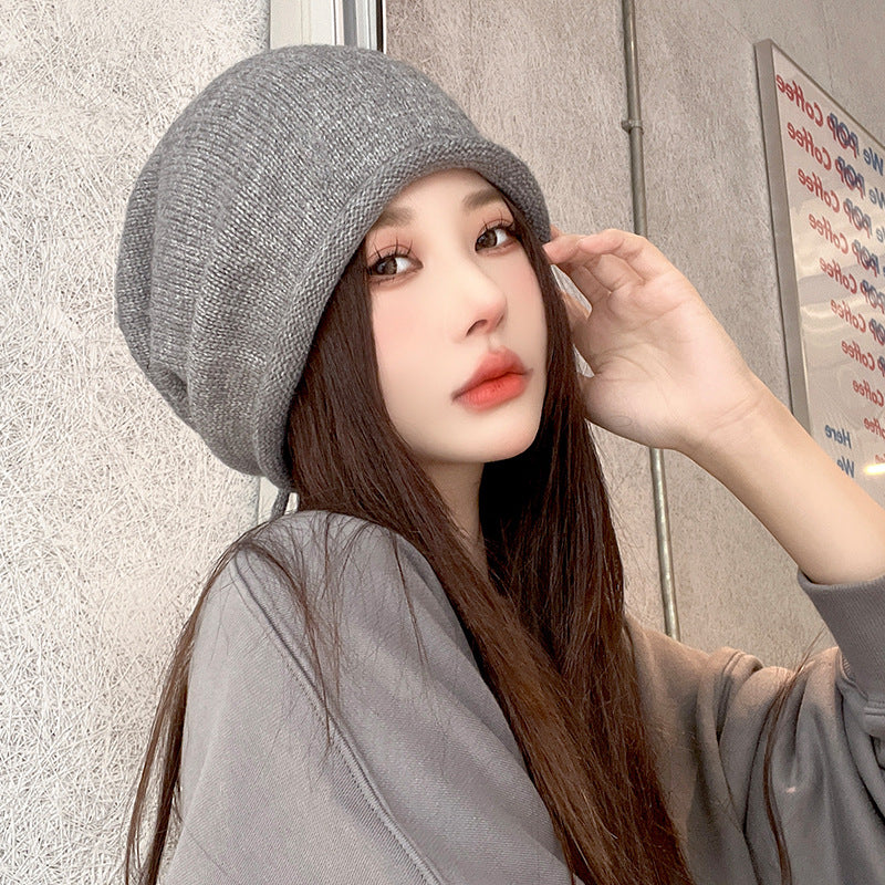 Close-up of gray slouchy beanie hat styled with long dark hair